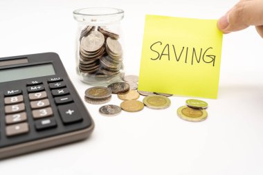 Yapışkan notta tasarruf metni ile para kavramı kaydediliyor. Finansal hedeflere ulaşmayı taahhüt ediyorum. Beyaz arka planda izole edilmiş. Tayland Baht Bozuklukları hesap makinesiyle döküldü.