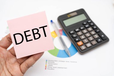 Hesap makinesiyle yapışkan notla ilgili DEBT metni. Ekonomik kriz riski ve sorun konsepti. Mali borç azalması, gelir yönetimi kavramı.