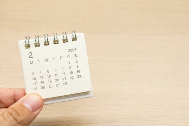 Şubat 2025 arkaplanı için el ele tutuşma mini takvimi. Takvim kavramı ahşap arka planda 2025 Şubat takvimi ile. Metin için Boşluğu Kopyala.