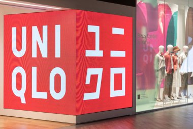 Uniqlo mağazası, Hızlı Perakende 'nin ticari markası, bir Japon giyim tasarımı. Uniqlo mağazasının penceresinden geçen insanlar.