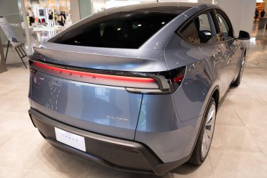 Stüdyoda yeni Tesla Model Y Juniper 2025, galeride elektrikli araç, açık bar.