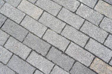 Kalıplı gri kaldırım taşları köşegen şeklinde dizilerek dayanıklı ve klasik bir açık hava yüzeyi oluşturur. Gri rengin pürüzlü dokusu ve değişen tonları doğal ve sağlam bir zemin sağlar..