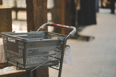 Modern bir perakende mağazasında tramvayda boş gri plastik bir alışveriş sepeti ya da bulanık arka planı olan bir süpermarket. Perakende sektörü, market alışverişi, günlük ayak işleri ve ticari reklamlar.
