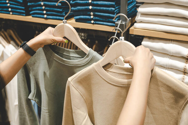 Ручной выбор скидки на одежду футболки в магазине, поиск или покупка дешевой хлопковой рубашки на вешалке вешалки на блошином рынке. Концепция магазинов.