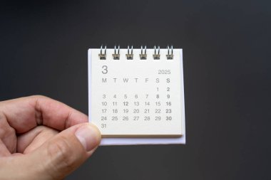 2025 Marşı için El Tutma Masası Takvimi. Koyu arkaplanda 2025 MAR takvimi olan takvim kavramı.