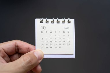 Ekim 2025 arka planı için El Tutma Masası Takvimi. Koyu arkaplanda 2025 OCT takvimi olan takvim kavramı.