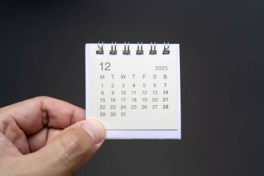 Aralık 2025 arka planı için El Tutma Masası Takvimi. Koyu arkaplanda 2025 DEC takvimi olan takvim kavramı.