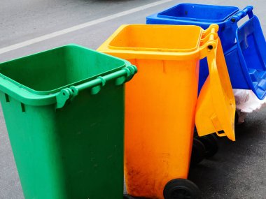 Atık Ayrıştırma için Çöp Kutuları. Caddenin kenarında yeşil, sarı ve mavi renkli üç renkli plastik çöp tenekesi. Çevreyi ve sürdürülebilirliği korumak için çöpleri ayırmanın önemi.