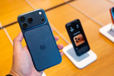 Hand holding a new Deep Blue iPhone 17 Pro Max in an Apple Store.