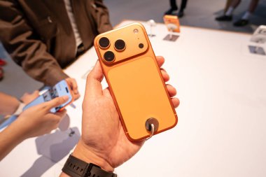 Hand holding a new iPhone 17 Pro Max in an Apple Store Central World. New Color Cosmic Orange. Copy Space
