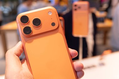 Hand holding a new iPhone 17 Pro Max in an Apple Store Central World. New Color Cosmic Orange. Copy Space