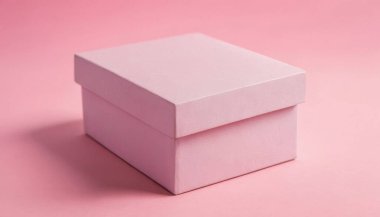 Pembe arka planda tek bir kapalı pembe hediye kutusu duruyor. Zarif ve temiz karton kutu ürünü için kaliteli fotoğraf modeli.