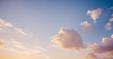 Yumuşak pembe ve mavi renkleri ve tüylü beyaz bulutları olan gün batımı gibi bir gökyüzü. Afişler, posterler ve duvar kağıtları için arkaplan fotoğrafları.