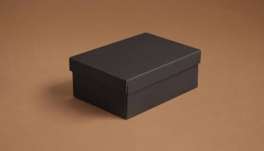 Kahverengi arka planda kapalı siyah karton kutu. Zarif ve temiz karton kutu ürünü için kaliteli fotoğraf modeli.
