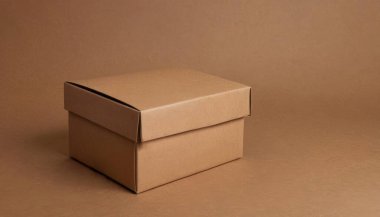 Kapalı karton kutu kahverengi desenli bir yüzeye oturur. Zarif ve temiz karton kutu ürünü için kaliteli fotoğraf modeli.