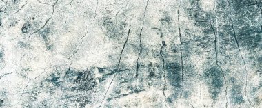 Close-up view of a cracked and weathered concrete surface, exhibiting a textured and distressed appearance.