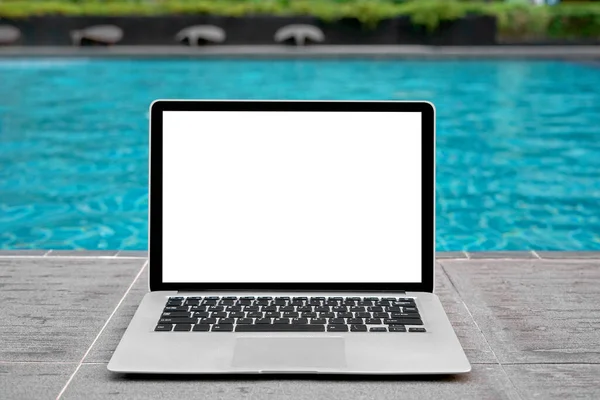 Laptop with blank screen for creative design on floor nearby swimming pool edge background. Computer notebook with monitor clipping path for present landing page design. Laptop computer mock up template