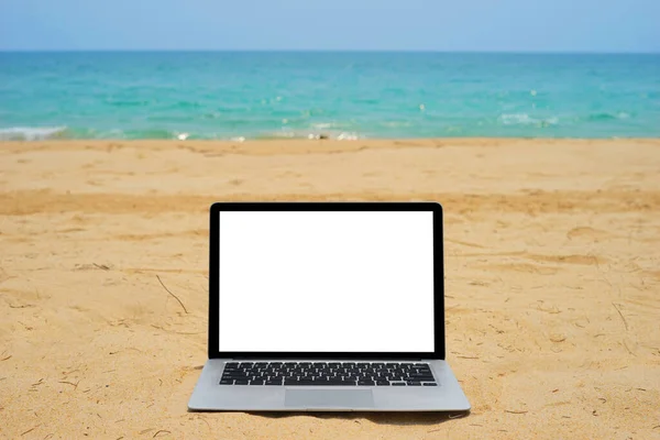 近くの青い海の背景に砂のビーチで創造的なデザインのための空白の画面を持つノートパソコン 現在のランディングページデザインのためのモニタークリッピングパスを持つコンピュータノートブック Mokupテンプレート — ストック写真