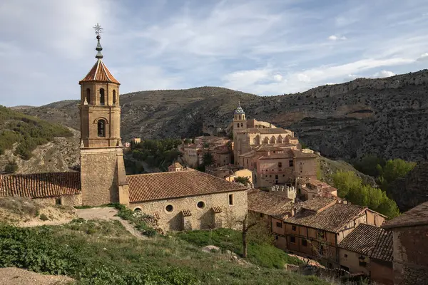 Gün batımında dağlarla çevrili ortaçağ güçlendirilmiş Albarracin köyünün çan kulesi..
