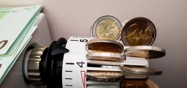 High cost of heating in Europe. A heating radiator thermostat on which there are a lot of two-euro coins. Significant rise in energy prices. Energy crisis and recession. 2 euro coins