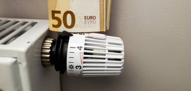 Radyatör bataryasının termostat sıcaklık kontrolöründe bir tomar euro banknotu var. Avrupa 'da yüksek ısıtma maliyetleri ve kışın elektrik fiyatlarında önemli bir artış. Enerji krizi ve durgunluk