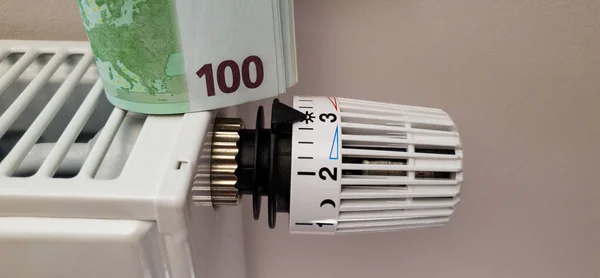 A stack of banknotes on the batteries of a central heating radiator. The concept of high heating costs and a significant rise in electricity prices in winter in Europe. Energy crisis and recession