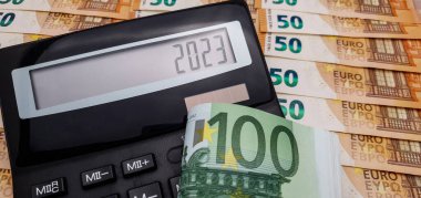 2023 'te Avrupa' da yaşamın enflasyon ve artan maliyeti. Hesap makinesi ve yığınla 100 avro banknot, arka planda 50 avro banknot