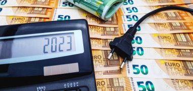 2023 'te enflasyon, kriz ve artan elektrik maliyeti. Hesap makinesi ve 100 avroluk banknotlar.