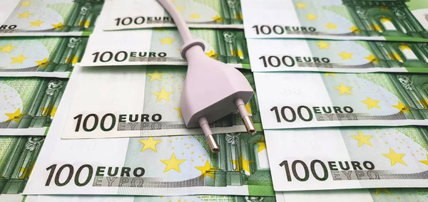 Electrical plug on 100 euro banknotes. The concept of rising cost of electricity, inflation and high cost of living