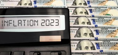 2023 'te dünyada yüksek enflasyon, enerji ve finansal kriz. Enerji, benzin, gıda ve malların sürekli artan maliyeti. Banknotların arka planında hesaplayıcı 100 Amerikan doları