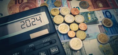 2024 yılında Avrupa 'da enerji ve mali kriz. Enerji, gıda ve malların sürekli artan maliyeti. Avro banknotlarının arka planında hesap makinesi ve bir sürü avro sikke
