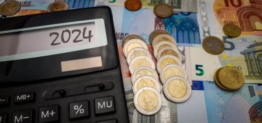 Avrupa 'nın 2024 enerji ve mali krizi. Enerji, gıda ve malların artan maliyetleri. Avro banknotları zemininde avro paralarıyla çevrili bir hesap makinesi