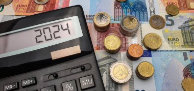 Promising prospects for euro strengthening in 2024. An abundance of banknotes, coins and a calculator symbolize financial growth. The calculator screen displays the year 2024 clipart