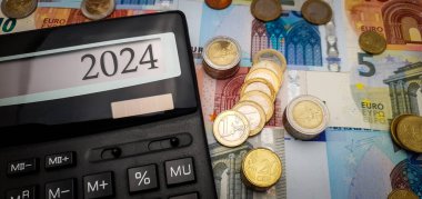 2024 yılında Avro 'nun gücü için umut verici bir görünüm. Banknotlar, madeni paralar ve finansal büyümeyi sembolize eden bir hesap makinesi. Hesap makinesi ekranı 2024 'ü gösterir
