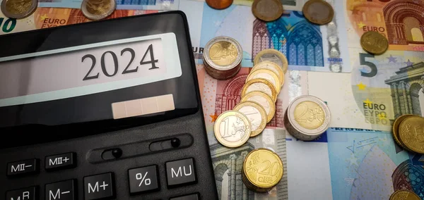 2024 yılında Avro 'nun gücü için umut verici bir görünüm. Banknotlar, madeni paralar ve finansal büyümeyi sembolize eden bir hesap makinesi. Hesap makinesi ekranı 2024 'ü gösterir
