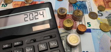 2024 yılında Avrupa 'da enerji ve mali kriz. Enerji, gıda ve mallar için hızla artan fiyatlar. Avro paraları ve banknotlarla çevrili hesap makinesi. Yeni Mali Yıl 2024