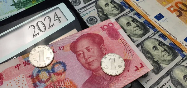 Energy and financial crisis in China in 2024. Constantly rising prices for energy, food and goods. Calculator and a lot of euro bills dollars and one bill of 100 Chinese yuan and two coins of one yuan