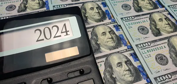 2024, the prospect of a financial and energy crisis in the world. Rising prices for energy, food and goods. Calculator on the background of a large number of banknotes of 100 dollars