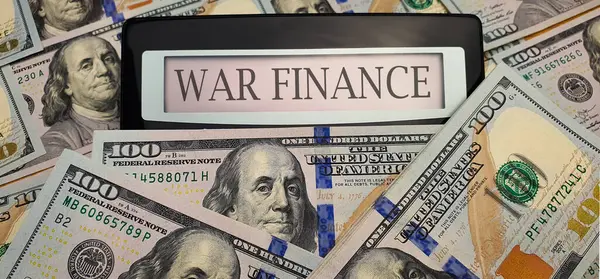 stock image War finance. A calculator surrounded by 100 US dollar bills. Concept of militarization, increase in spending on weapons for defense, arming the army, training the military, fighting terrorism