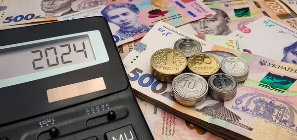 ウクライナの2024年新年 戦争と危機 ウクライナの紙幣と硬貨の背景にある計算機 インフレ 経済危機 景気後退 — ストック写真
