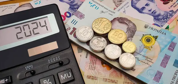 ウクライナの2024年新年 ウクライナの紙幣と硬貨の背景にある計算機 インフレ 景気後退 生活費 — ストック写真