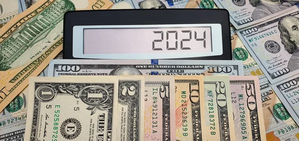 Military spending and the new year 2024. Calculator on the background of US dollar banknotes. USA, Europe, crisis, recession, inflation, cost of living, war, investments, accounts, poverty, border