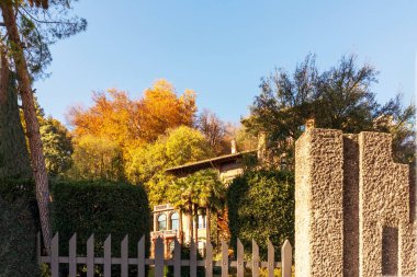 Beyaz bir özel ev manzarası ve sonbahar ağaçlı bir bahçe.