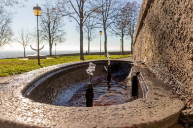 Su, mavi gökyüzü ve yeşil çimenli mason çeşmesi