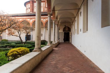 Courtyard of a house with a walking garden and white building columns on a clay cobblestone path