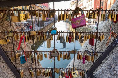 Lots of small and interlocking keys on the bridge railing and a view of the canal water through them