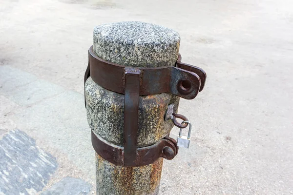 Aertical stone pillar with metal hammers on a locked key on it