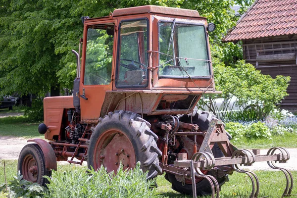 緑の庭の背景にオレンジの色の古いファームトラクター — ストック写真