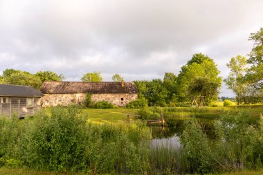 Arkasında ağaçlar olan bir tarlada ahşap bir ahır.