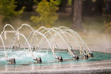 Bir çeşme, arka plana su ve buhar püskürtür.